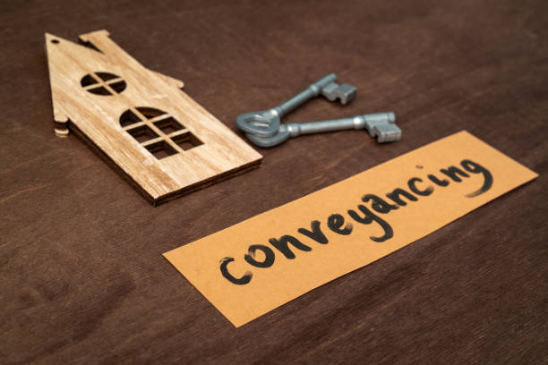 r15 a cut out wooden house representation with a key and a card saying 'conveyancing' on wood background