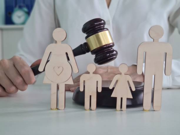 A judge holds a gavel above wooden figures representing a family